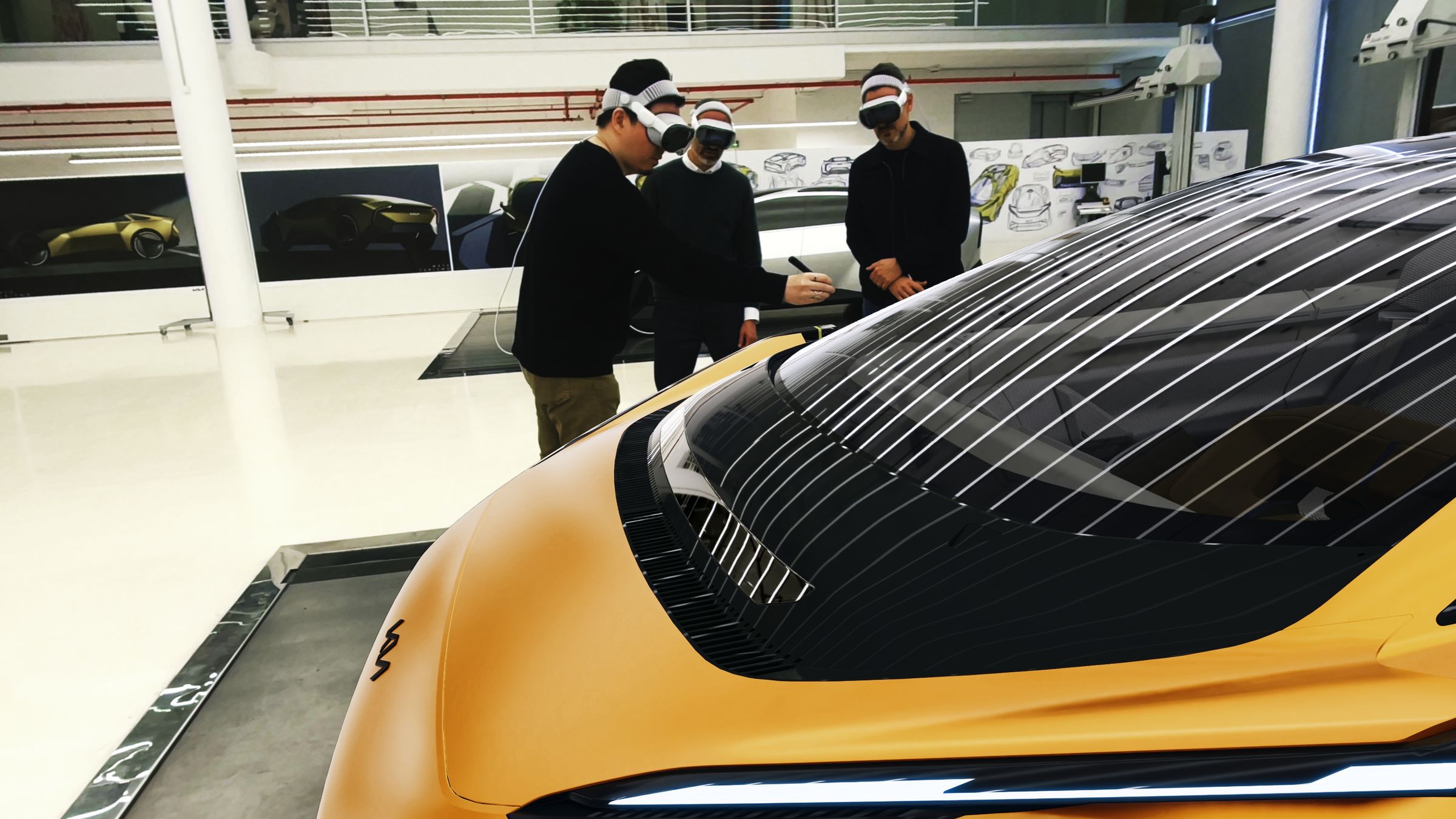 Three Kia designers wearing Apple Vision Pro reviewing a yellow concept car together.