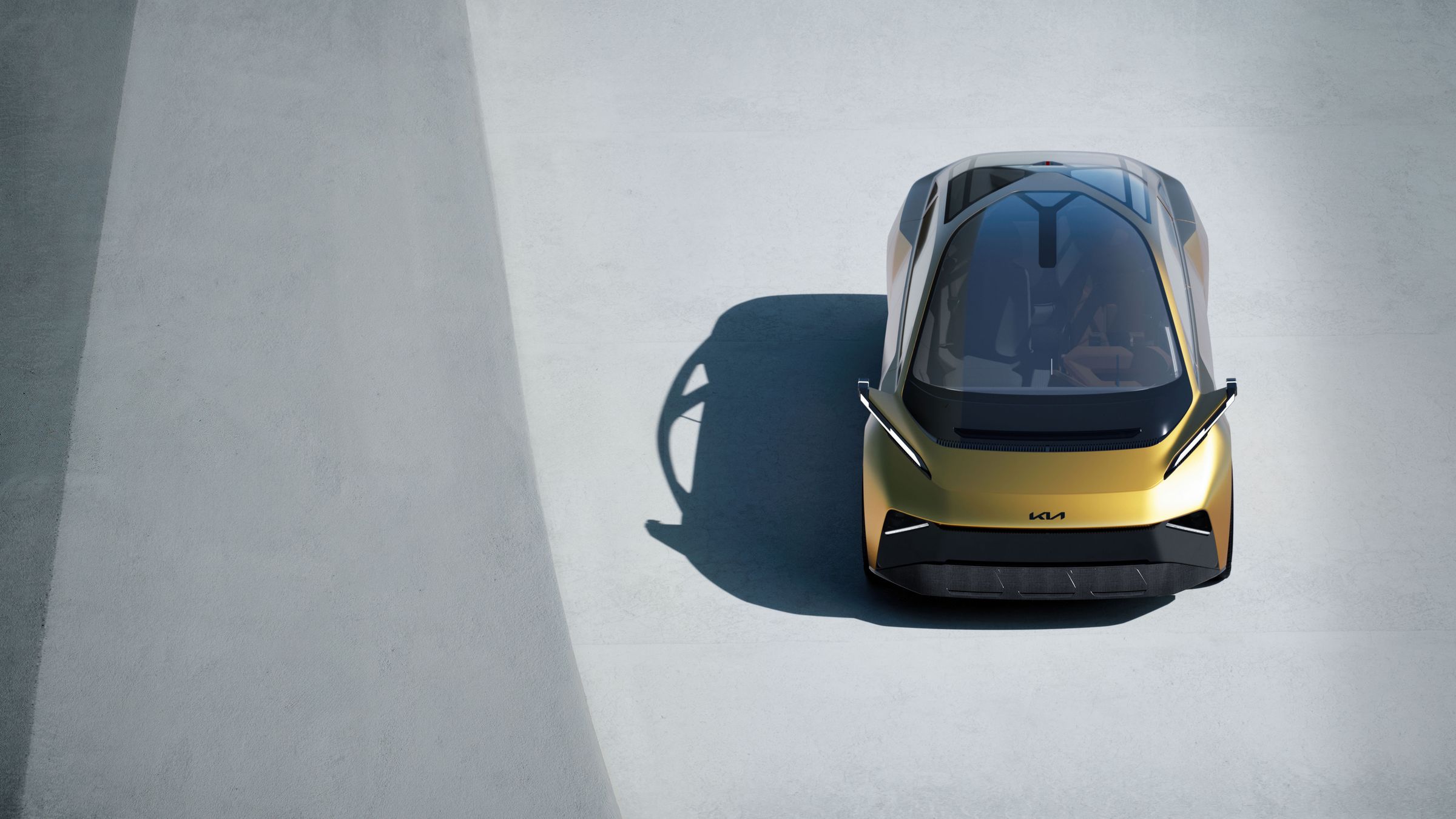 Top-down view of the KIA Metavision concept car in gold-yellow with the KIA logo, parked on a concrete floor